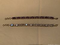 Top view of two sterling silver bracelets; one with amethyst round stones, one with oval moonstone and clear stones.