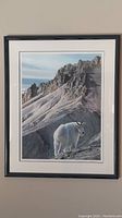 Full view of framed and matted print depicting a mountain goat in a mountainous environment.