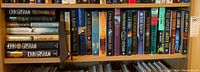 Shelf with multiple hardcover novels by John Grisham, Nora Roberts, Julie Garwood.