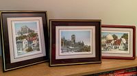 Three framed prints of Quebec City landmarks displayed on a shelf, showing varied frame colors and sizes, largest approximately 10x12 inches.
