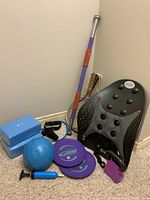 Full view of all items in lot including racquets, yoga blocks, inflatable ball, pump, gliding discs, Dr Hos back support, kettle bell, pull-up bar, and resistance band.