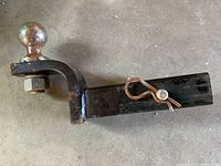 Side view of the trailer hitch showing the 2-inch ball and bent shank with pin and clip attached.
