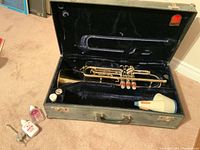 Open black hard-shell case showing trumpet and accessories