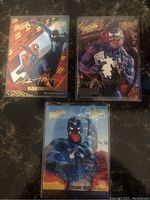 Two photos showing eight Marvel Fleer Ultra Spider-Man trading cards each with gold foil autographs. Characters include Spider-Man, Venom, Carnage, Black Widow, Human Torch, and Kingpin.