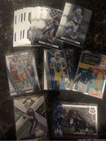 Top view of NFL football cards spread out showing players Mac Jones and Justin Herbert with prizm and mosaic card designs