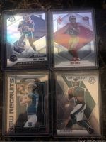 Eight NFL rookie football cards featuring Mac Jones, Jalen Hurts, Trey Lance, Trevor Lawrence, Tua Tagovailoa, and Justin Fields in protective sleeves on a dark marble surface.