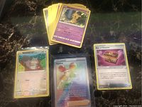 Photo showing the lot's key cards including a rainbow holo Fantina card, Slowmet, Box of Disaster, and assorted other Pokémon cards.