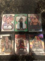 Photo showing six WWE trading cards including The Rock, Braun Strowman, Stone Cold Steve Austin 'Fearless', Chris Jericho 'Next Level' cards with holographic and prism finishes.