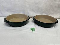 Two oval Pampered Chef Heritage Family stoneware dishes shown side by side, hunter green exterior and beige interior, in excellent condition.