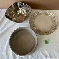 View of all three items: a round concrete planter, a hammered metal bowl, and a glass platter with shell and starfish decorations.