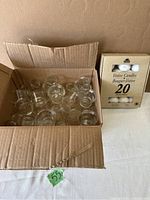 Box containing approximately 33 clear glass votive candle holders.
