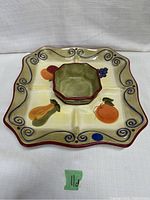 Square ceramic platter with scalloped edges and painted fruit and vegetable motifs, with removable octagonal dip bowl placed in the center compartment