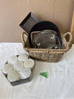 Overall view of the woven basket filled with candle holders and the sealed pack of tealight candles beside it.