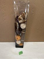 Photo of the full set of assorted dried botanicals in a clear plastic container showing natural shades and shapes for decorative use.