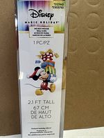 Front view of packaging showing Disney Magic Holiday branding and Mickey Mouse illustration on the wall cling, specifying size 2.1 ft tall