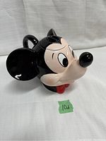 Front angled view of Mickey Mouse head-shaped teapot showing face, ears, and ear chip.