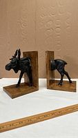 Side profile of the pair of moose bookends on wood bases with a ruler for scale.