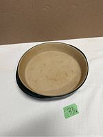 Top view of round stoneware dish showing beige interior and dark green exterior.