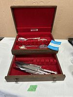 Oneida wooden chest with red felt lining containing silver butter spreaders and other silver utensils.