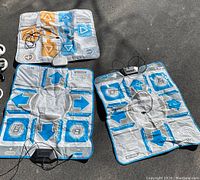 Three Nintendo Wii dance floor pads laid out showing arrow buttons and wired connectors.