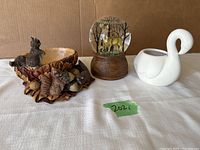 Overview of all three items in the lot: snow globe with deer, squirrel egg dish, and white swan planter