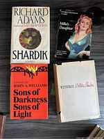 Top-down view of the four vintage hardcover books stacked to show each cover: Shardik, Millie's Daughter, Sons of Darkness Sons of Light, and Witness.