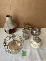Photo of all six candle holders including the pottery outdoor fireplace style holder and various metal tea-light holders with cutout designs.