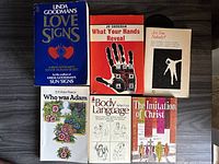 Top-down view of 6 paperback books arranged on a dark surface showing their covers.