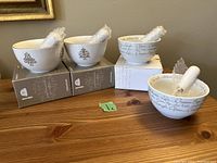 Four Bowring spread dishes and matching spreaders on table, two dishes with tree design and two with script text, spreaders wrapped in bubble wrap.