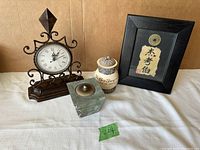 Photo showing all items together: clock, framed coin, beige decorative candle holder with lid, glass cube candle holder