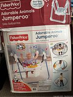 Box of Fisher-Price Adorable Animals Jumperoo showing product information and images of the jumperoo assembled with baby using it, highlighting features like music, sounds, lights, and adjustable height.