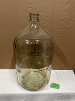 Front view of the 5 gallon glass jug showing its square pattern design, rounded shoulder, and clear transparent glass