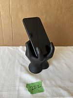Black hand-shaped holder holding a cell phone upright.