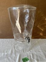 Front view of the large clear acrylic drink dispenser with attached metal spigot at the bottom of the liquid chamber.