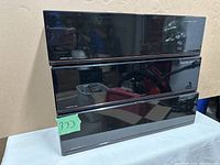 Three black Laserline branded CD storage units stacked, all closed showing glossy front panels with Laserline logo.