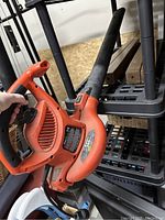 Side view of orange electric leaf blower showing handle, vents, and black nozzle