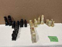 Full view of black and white onyx chess pieces arranged, black set missing one pawn as noted