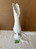 Front angled view of tall white hobnail milk glass vase showing ruffled top and pedestal base.