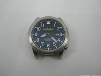 Front view of Cabela's Momentum watch face showing black dial with white numerals, yellow second hand, date window, and stainless steel bezel.