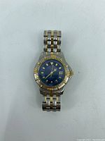 Front view of Caravelle by Bulova watch showing blue dial with gold-tone hour markers and two-tone metal band.