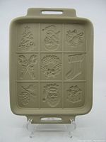 Front view of the ceramic shortbread cookie tray showing nine Christmas themed embossed sections including a Christmas tree, snowman, bell, candy canes, wreath, stocking, pinecone, Santa face, and gift box.