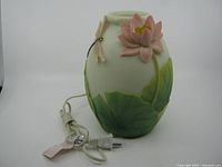 Front view of the vintage ceramic table light showing the pink lotus flower, dragonfly detail, green lotus leaves, and attached power cord.