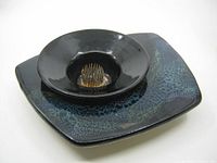 Angled side view of Ikebana ceramic flower vase showing the dark blue and black glaze with metal floral frog in the center.