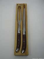 Full view of the Laguiole carving knife and fork in a fitted wooden tray, highlighting handle design and metal accents.