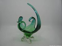 Front side view of blue-green handblown art glass dish with clear base and curved handle