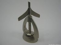 Front and side view of vintage metal rocket-shaped nut cracker with screw press mechanism