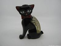 Front view of black ceramic cat letter holder showing facial details and attached metal spring pencil holder on the back.