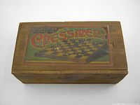 Closed original wooden box with colorful label 'Superior Quality Chessmen' on top. Shows wood grain and minor wear marks.