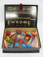 Open Black Magic chocolate box displaying 13 vintage bubble lights with colorful tops and screw bases on pink tissue paper.