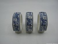 Front view of three Churchill Blue Willow pattern napkin rings in a row showing detailed pattern